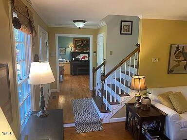 hallway featuring wood finished floors, stairway, and ornamental molding