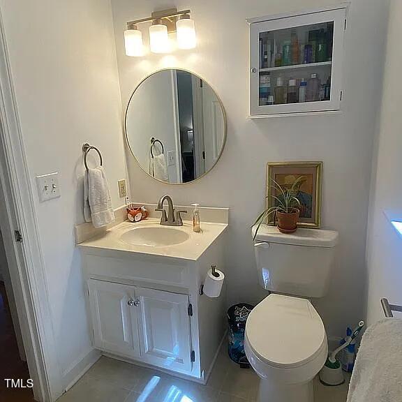 half bathroom with toilet, vanity, and baseboards