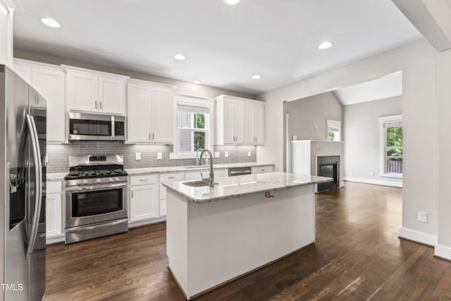 3914 Old Chapel Hill Rd, Durham, NC 27707 - kitchen featuring appliances with stainless steel finishes, a sink, decorative backsplash, white cabinets, and a center island with sink