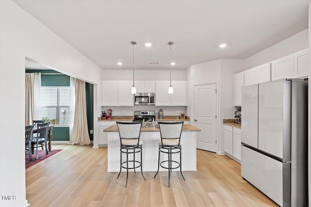 637 Marrian Dr, Clayton, NC 27520 - kitchen featuring stainless steel appliances, light wood-style floors, white cabinetry, a kitchen island with sink, and recessed lighting