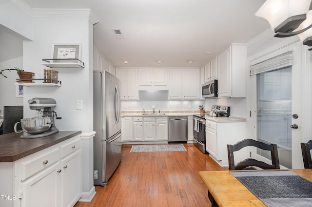 200 W Woodcroft Pkwy Unit 57B, Durham, NC 27713 - kitchen featuring stainless steel appliances, a sink, white cabinets, light wood-style floors, and crown molding
