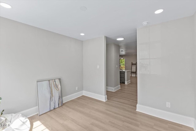 empty room featuring light wood finished floors, baseboards, and recessed lighting