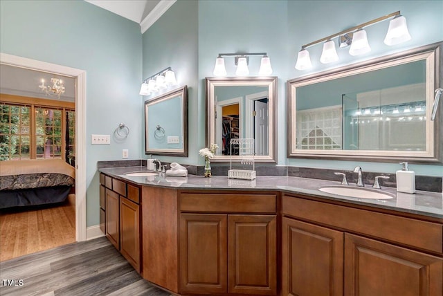 ensuite bathroom featuring wood finished floors, double vanity, and a chandelier