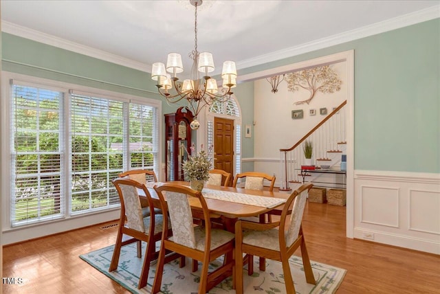 dining room featuring wainscoting, ornamental molding, stairs, and a chandelier