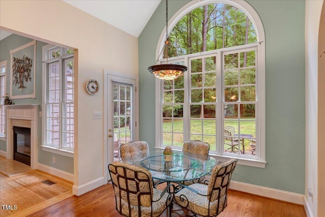 dining room with plenty of natural light, light wood-style flooring, baseboards, and vaulted ceiling