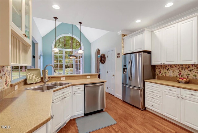kitchen featuring stainless steel appliances, a sink, white cabinetry, light wood-style floors, and decorative light fixtures