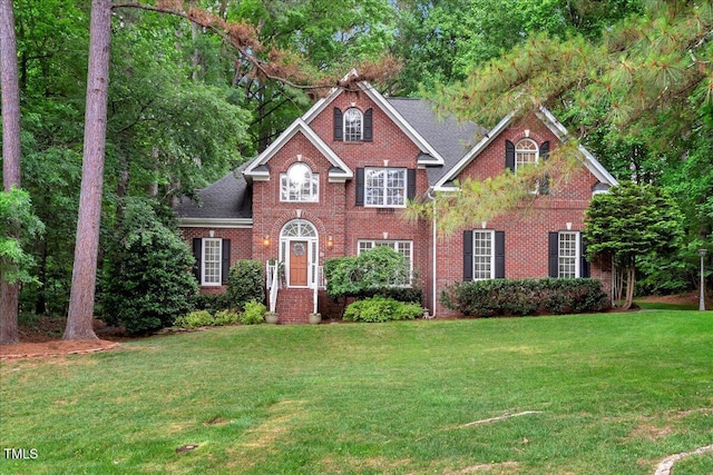 view of front of home with brick siding, a front lawn, and a shingled roof