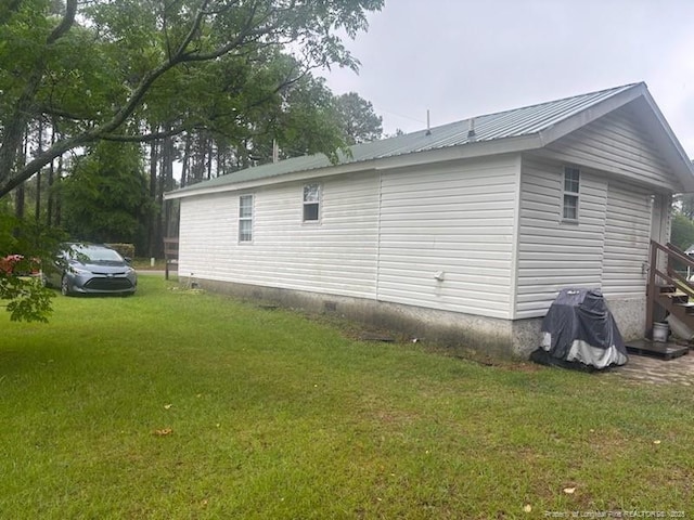 view of side of home featuring a lawn and metal roof