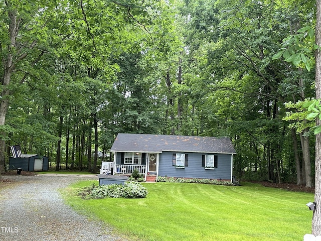 view of front of property with a shed, an outdoor structure, a porch, gravel driveway, and a front lawn