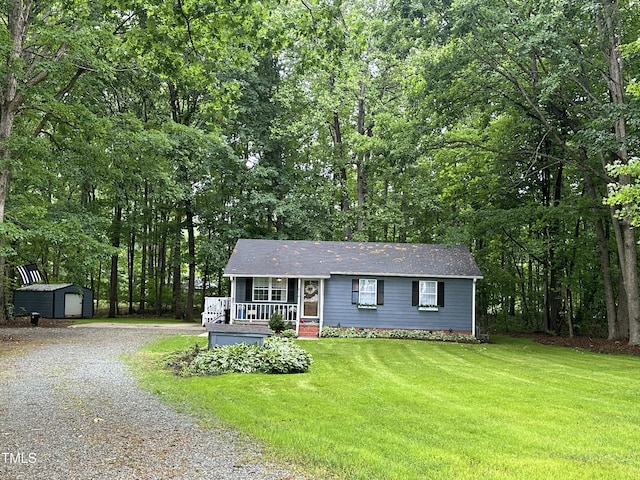 view of front of house featuring an outdoor structure, a front lawn, covered porch, gravel driveway, and a shed