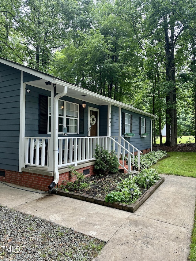 ranch-style home with a porch and view of scattered trees