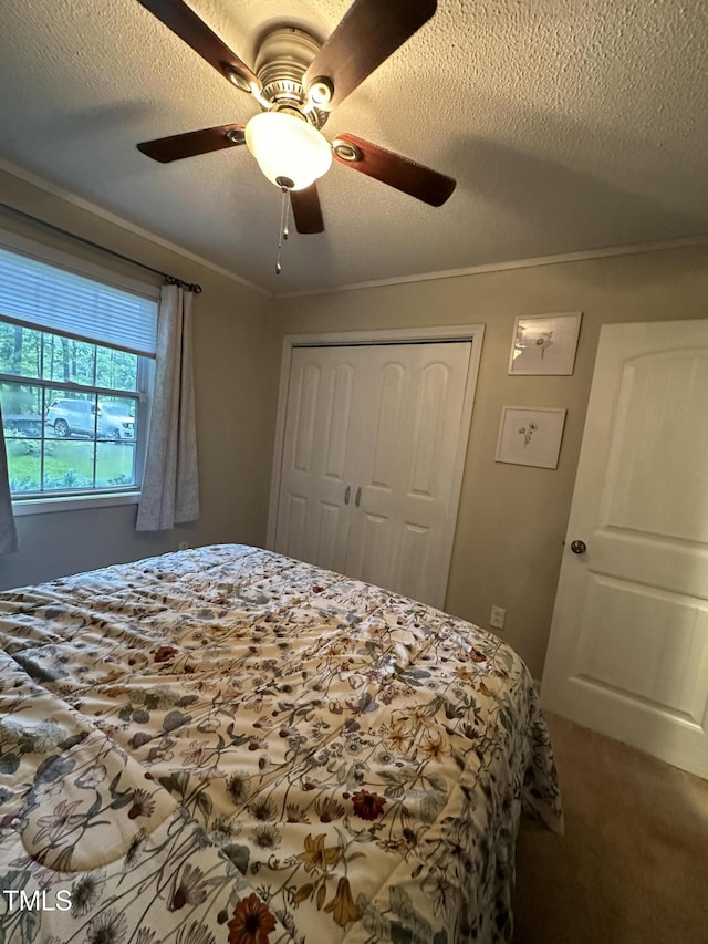 bedroom featuring a closet, ceiling fan, a textured ceiling, ornamental molding, and carpet flooring