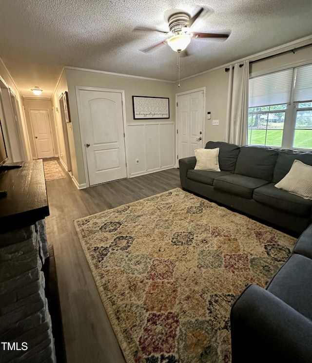 living area featuring ceiling fan, dark wood finished floors, a textured ceiling, and baseboards