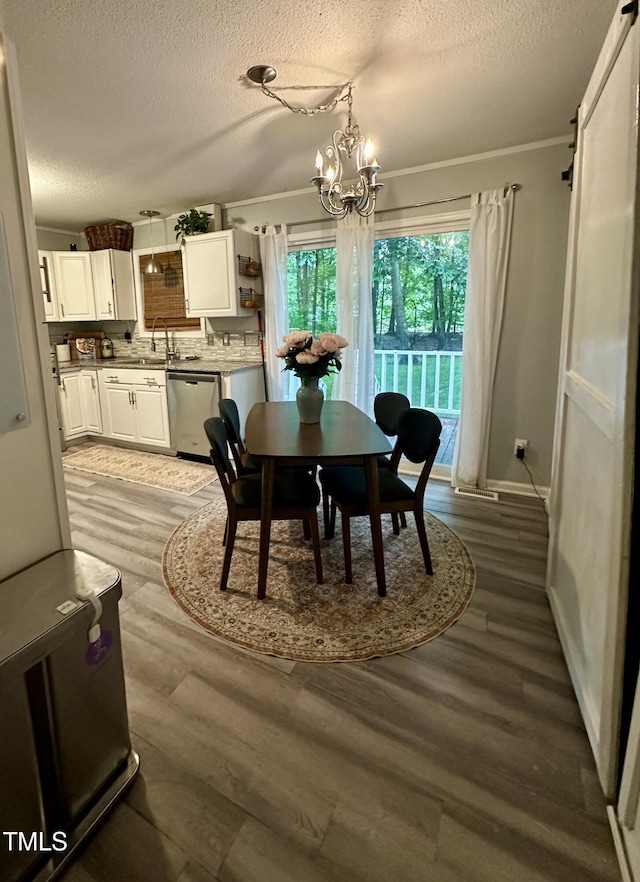 dining space with a textured ceiling, a chandelier, light wood-type flooring, baseboards, and ornamental molding