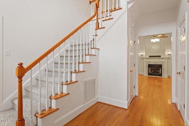 6335 Cedar Waters Dr, Raleigh, NC 27607 - stairway featuring wood finished floors, a fireplace, a ceiling fan, and baseboards