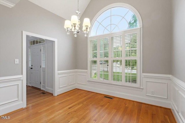 6335 Cedar Waters Dr, Raleigh, NC 27607 - unfurnished dining area with a chandelier, healthy amount of natural light, a decorative wall, a wainscoted wall, and light wood-style flooring