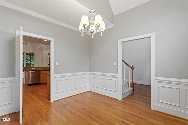 6335 Cedar Waters Dr, Raleigh, NC 27607 - spare room with stairs, a chandelier, light wood-style floors, vaulted ceiling, and wainscoting