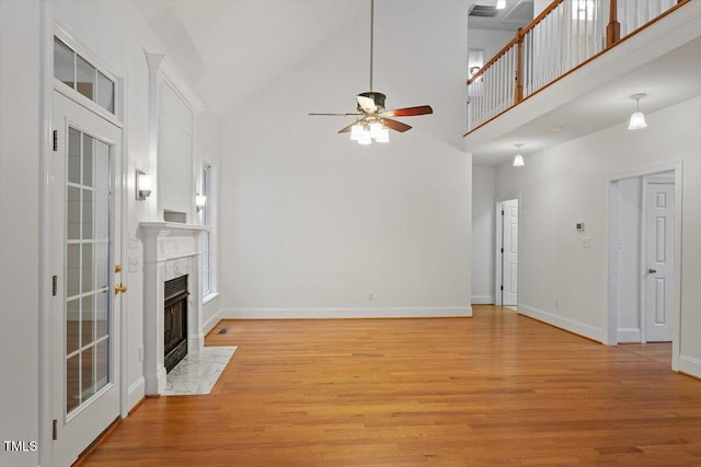 6335 Cedar Waters Dr, Raleigh, NC 27607 - unfurnished living room with a ceiling fan, light wood-type flooring, a premium fireplace, a high ceiling, and baseboards