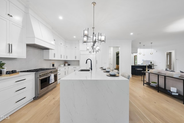 kitchen with high end stainless steel range, premium range hood, a sink, white cabinets, and recessed lighting
