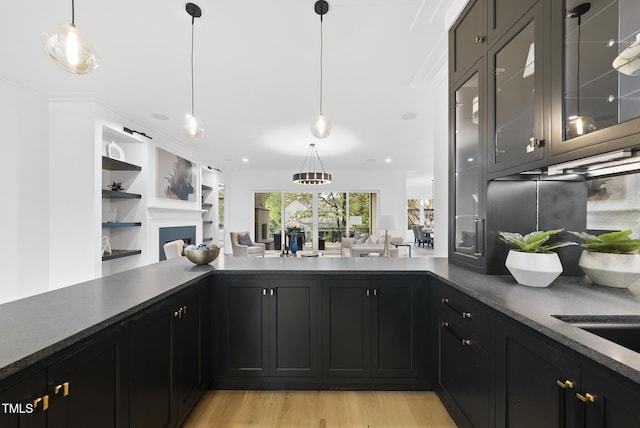 kitchen with open floor plan, light wood-style floors, dark countertops, decorative light fixtures, and recessed lighting