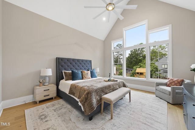 bedroom with high vaulted ceiling, light wood-style floors, baseboards, and ceiling fan