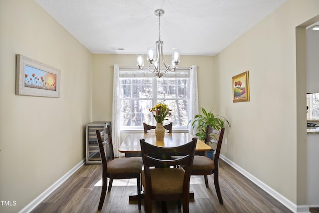 dining space featuring a chandelier, dark wood finished floors, and baseboards