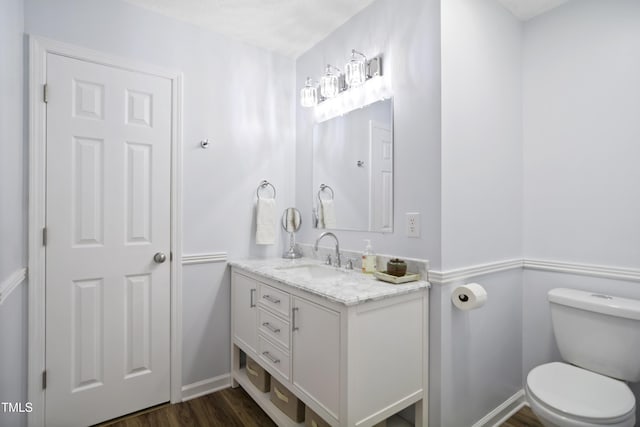 bathroom featuring toilet, vanity, wood finished floors, and baseboards
