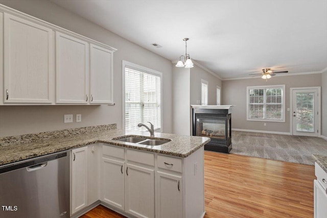 kitchen featuring stainless steel dishwasher, a sink, a peninsula, white cabinets, and open floor plan