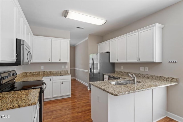 kitchen featuring stainless steel appliances, baseboards, a peninsula, and wood finished floors