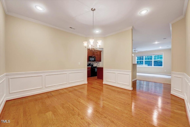 unfurnished dining area with a chandelier, a decorative wall, light wood-type flooring, wainscoting, and crown molding