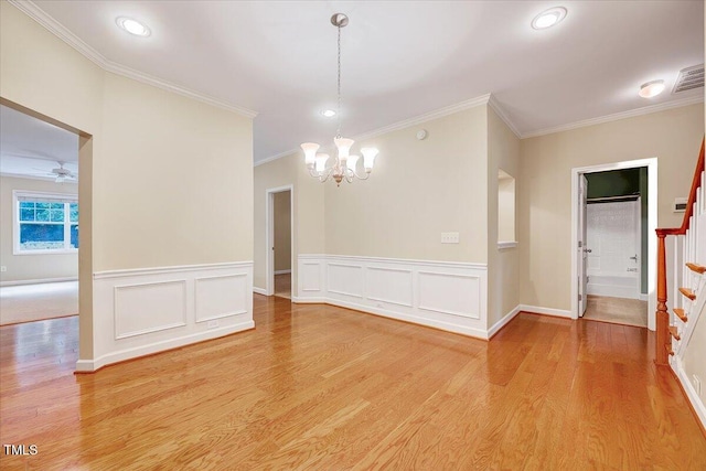 unfurnished dining area featuring a chandelier, crown molding, light wood finished floors, stairway, and a wainscoted wall