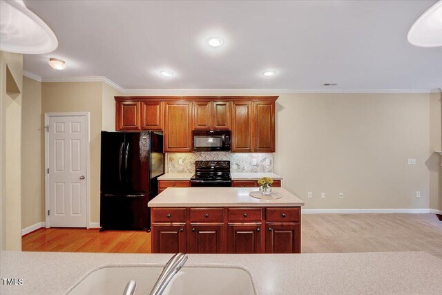 kitchen featuring black appliances, light countertops, ornamental molding, backsplash, and baseboards