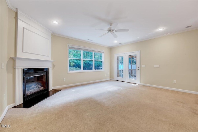 unfurnished living room with ornamental molding, ceiling fan, a glass covered fireplace, baseboards, and light colored carpet
