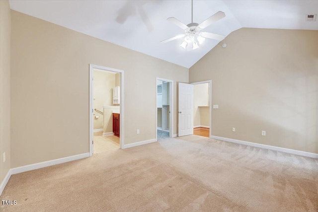 unfurnished bedroom with a walk in closet, light carpet, a closet, ensuite bathroom, and high vaulted ceiling