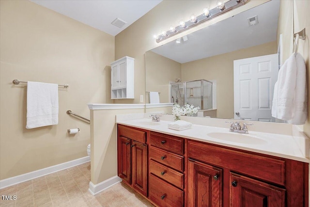 bathroom with baseboards, a stall shower, double vanity, and toilet
