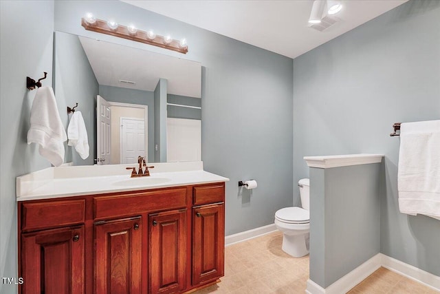 bathroom featuring toilet, vanity, and baseboards