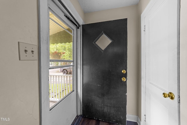 doorway featuring dark wood-style floors and baseboards