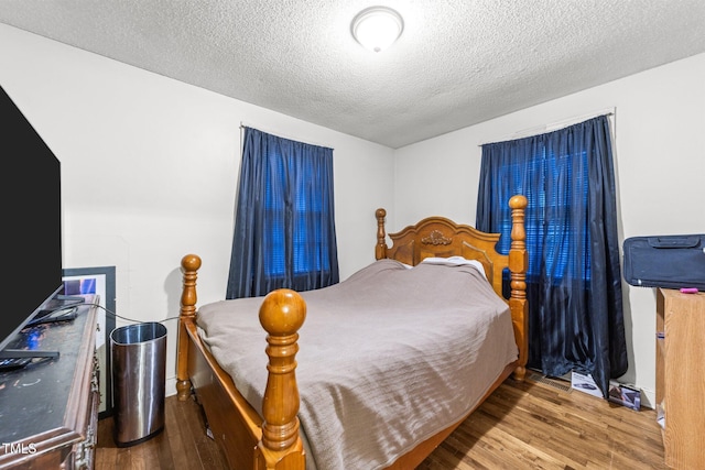 bedroom featuring wood finished floors and a textured ceiling