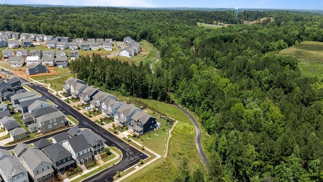 aerial view of property's location featuring a forest and nearby suburban area