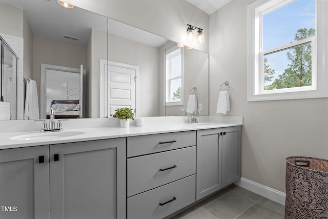 bathroom featuring healthy amount of natural light, double vanity, baseboards, and connected bathroom
