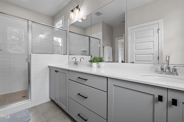 full bath with a stall shower, double vanity, and tile patterned flooring