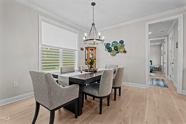 dining area featuring a chandelier, light wood-style floors, crown molding, and baseboards