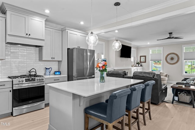 kitchen with appliances with stainless steel finishes, open floor plan, light wood-type flooring, crown molding, and recessed lighting