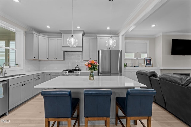 kitchen featuring stainless steel appliances, a sink, open floor plan, a kitchen breakfast bar, and recessed lighting