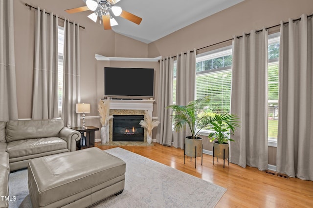 living room with a ceiling fan, wood finished floors, vaulted ceiling, and a fireplace