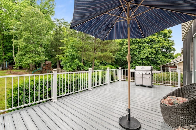 wooden terrace featuring a playground, view of wooded area, and area for grilling