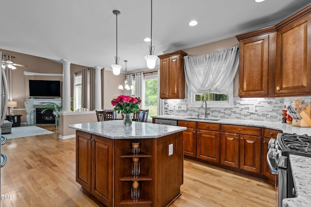 kitchen featuring a sink, stainless steel appliances, open floor plan, decorative backsplash, and light stone counters