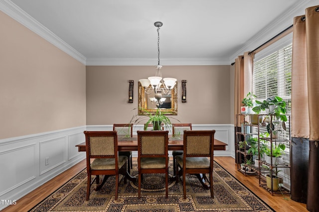 dining space with a chandelier, ornamental molding, light wood-style flooring, and wainscoting