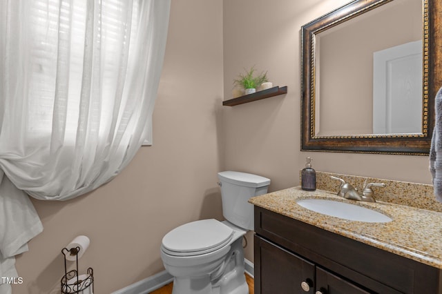 bathroom with toilet, baseboards, and vanity