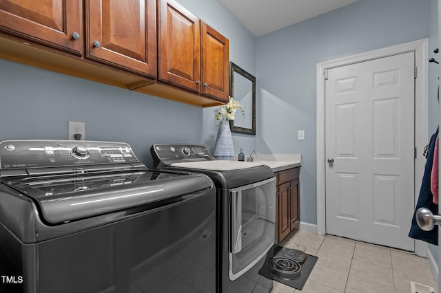 washroom with washer and clothes dryer, cabinet space, light tile patterned flooring, and baseboards